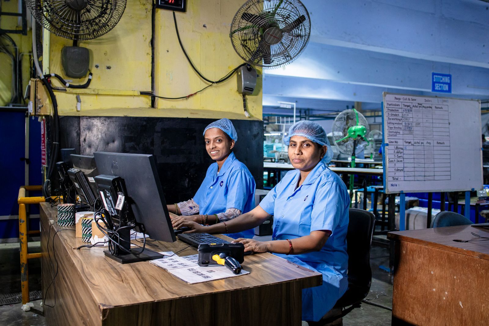 Two staff at a computer with paper files