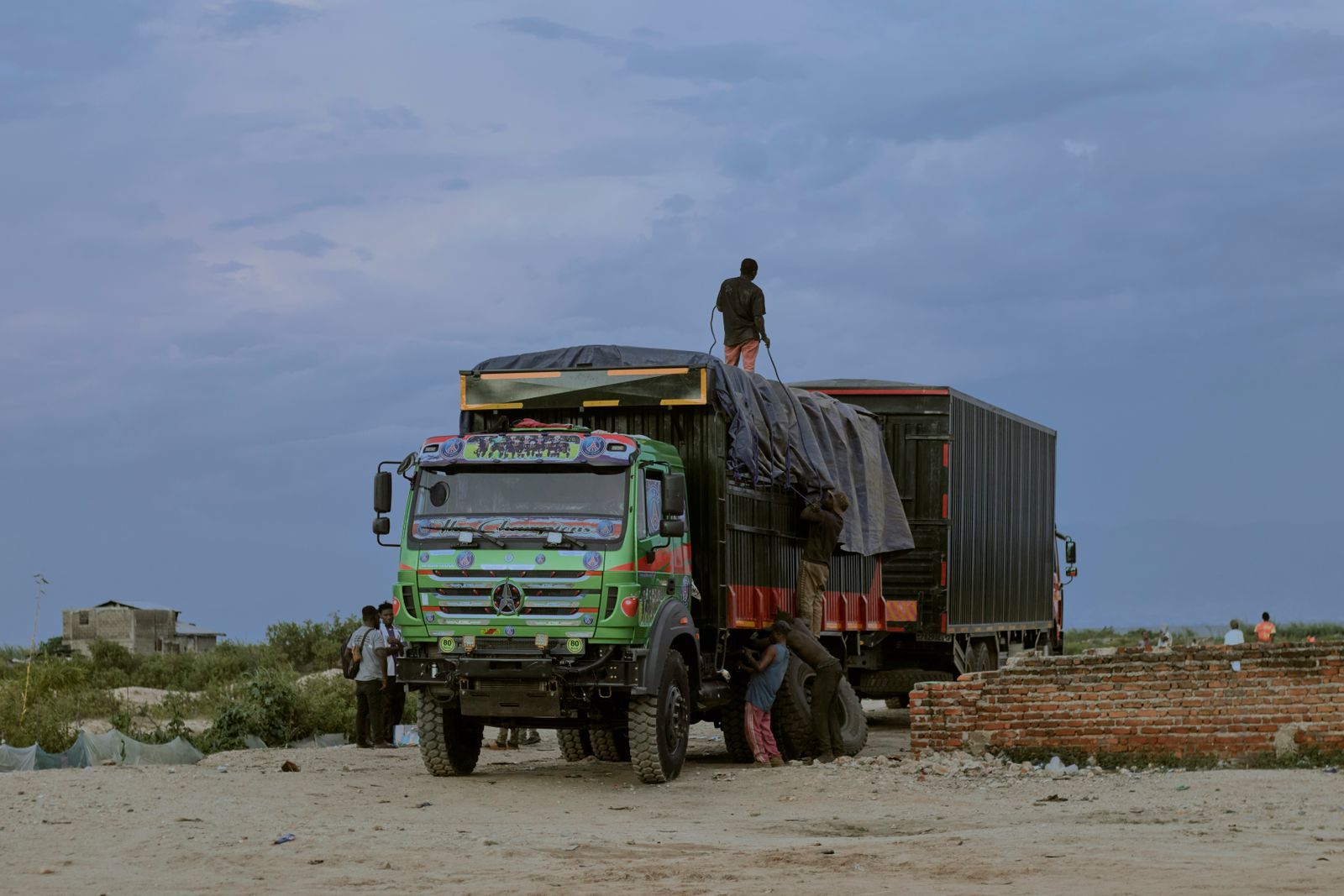 A loaded goods truck with workers securing cargo